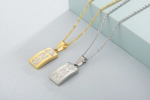 Detailansicht rechteckiger Gold- und Silberanhänger mit Strasssteinen und PNG-Buchstaben