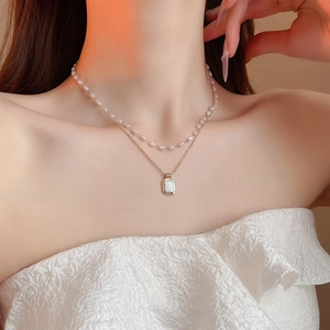 Macro view of French retro double-layer necklace with pearl strand and gold pendant