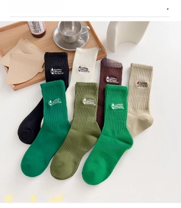 Detail of seven colored cotton crew socks featuring outdoor camping embroidery and rib knit