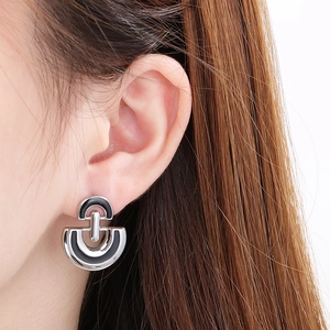 Close-up of D-shaped silver stainless steel earrings with black enamel on model's ear