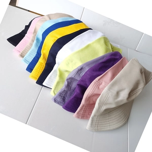 Flat lay of cotton bucket hats in multiple colors on a white wood texture background
