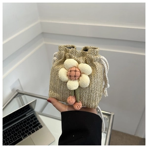 Dettaglio della mini borsa a secchiello in paglia con grande fiore 3D e pompon rosa