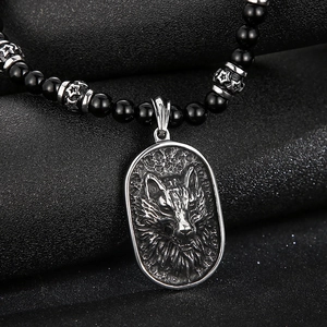 Macro shot of punk wolf head pendant with black agate beads on steel necklace
