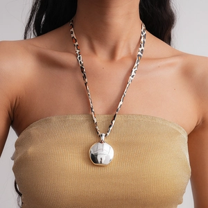 Détail du collier léopard vintage avec un grand pendentif rond argenté poli sur modèle
