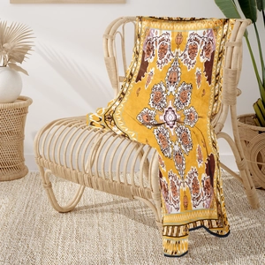 Bohemian yellow flannel blanket with mandala patterns on a stylish rattan armchair