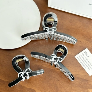 Three elegant black bow hair claws with Grace lettering on a minimalist wooden table