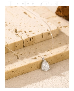 Detailed view of pear-cut moissanite pendant on transparent fishing line silver necklace