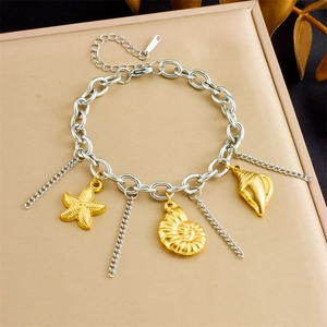 Detailed view of marine charm bracelet with starfish and shell on a gold tray