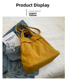 Lemon yellow nylon tote bag displayed on white fabric with books and a denim jacket