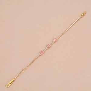 Elegant gold bracelet with square pink stones and zircon accents on beige background