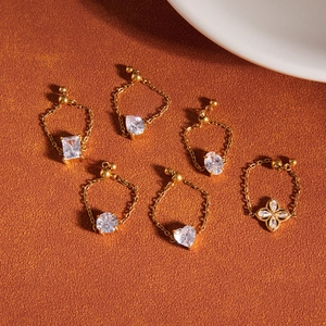 Adjustable gold chain rings featuring various cubic zirconia shapes on a textured surface