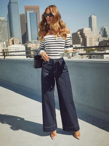 Draußen-Aufnahme einer Frau in High-Waist-Jeans mit weitem Bein und Streifen-Top