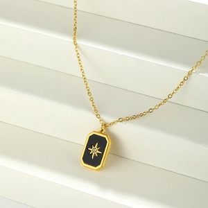Macro shot of rectangular gold-plated pendant with black enamel and star motif
