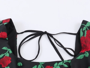 Détail du tissu jacquard à roses rouges avec bretelles noires nouées sur la robe