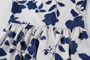 Detailaufnahme eines Kleides mit Blumenmuster, marineblauen Blüten und Taillenplissee
