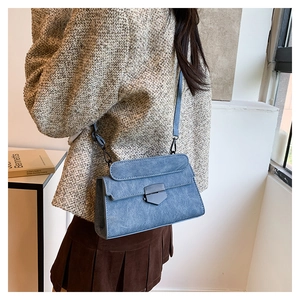 Detail of blue vintage crossbody bag featuring a matte metal buckle and suede texture