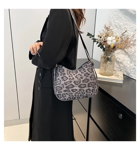 Chic grey leopard print crescent shoulder bag worn by a model in a stylish home setting