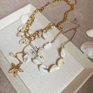 Detail of gold starfish and seashell charms on layered pearl beach vacation necklaces