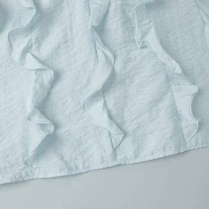 Detailed view of light blue ruffled texture and breathable fabric on a V-neck blouse