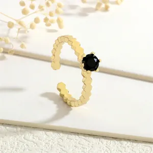 Detail of 18K gold ring with a black gemstone and textured honeycomb band design