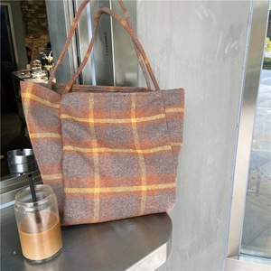 Detailed view of the plaid woolen tote bag texture in a casual cafe lifestyle setting