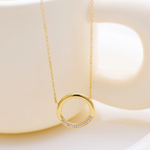 Détail macro d'un collier doré 18 carats avec pendentif rond serti de zircons blancs