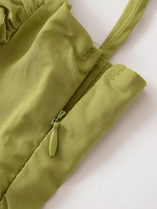 Dettaglio del top verde oliva con cerniera invisibile e texture in tessuto di cotone e lino