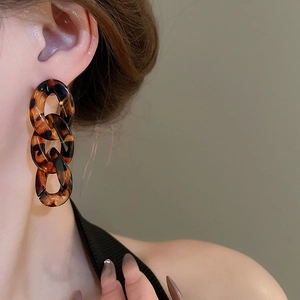 Close-up of amber tortoiseshell chain earrings with three interlocking resin links