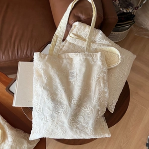 Detailed close-up of ivory lace embroidery floral pattern on a vintage cotton tote bag
