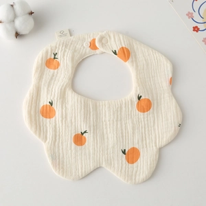 Detail of petal-shaped cotton gauze baby bib with orange print and snap button