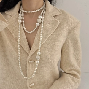 Detail of layered pearl necklace with pavé crystal balls on tweed jacket background