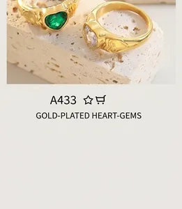 Detailed view of vintage gold heart rings with inlaid green and clear gemstones