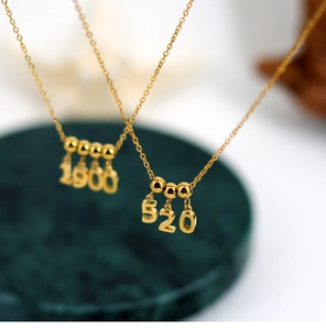 Macro shot of 1900 and 520 gold number pendants with polished metal finish and fine chain