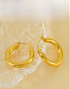 Detailed view of polished 18K gold chunky hoop earrings on elegant silk background