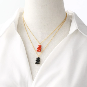Double-layered gold necklace featuring colorful resin gummy bear pendants on white background