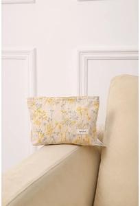 Détail d'une trousse en lin beige avec broderie florale sur l'accoudoir du canapé