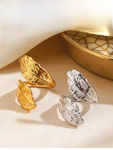 Macro shot of gold and silver feather rings featuring detailed leaf vein textures and adjustable bands