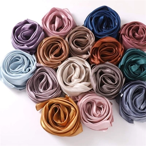 Lustrous solid color satin scarves in various shades rolled into decorative floral shapes