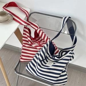 Vue détaillée de dessus de grands sacs fourre-tout en toile rayée rouge et bleue