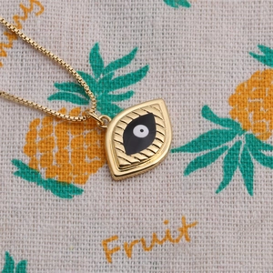 Detail of gold evil eye pendant with black and white enamel on a gold box chain necklace