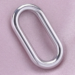 Close-up of a polished silver stainless steel oval pendant on a textured fabric background