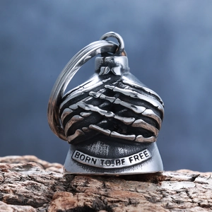 Detail of vintage skull bell pendant with Born To Be Free engraving on textured bark