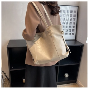 Grand sac cabas beige en cuir avec détails dorés porté par un mannequin en studio