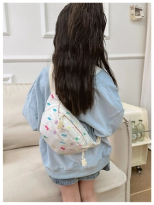 Kid's white chest bag with candy prints worn by a child in a home setting