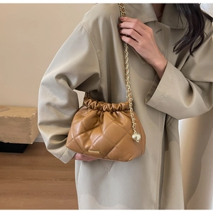 Detailed view of caramel quilted chain bag with gold ball adjuster on a female model