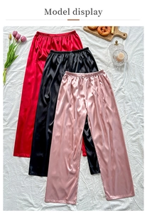 Flat lay detail of satin lounge pants in red, black, and pink with elastic waist and silk texture
