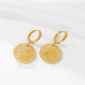 Détail macro de boucles d'oreilles dorées en acier inoxydable à effet martelé