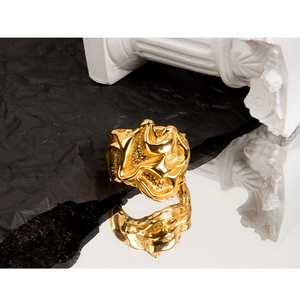Artistic close-up of golden irregular textured ring with abstract molten flower design