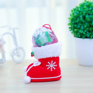 Detail of red flocked Christmas boot filled with candies and holly leaf accents