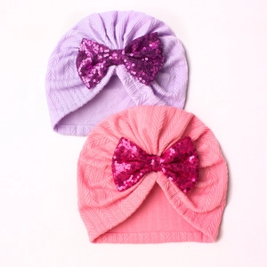 Detail of baby knit beanies in pink and purple with large sequin bow decorations